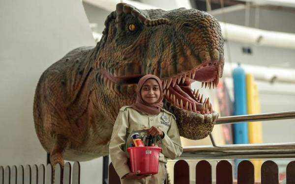 Nur Syahirah yang juga tukang jahit replika dinosaur bergambar bersama seekor daripada 18 ekor replika dinosaur animatronic yang diselenggaranya pada Pameran Dinosaur Encounter di Pusat Sains Negara baru-baru ini. Foto Bernama