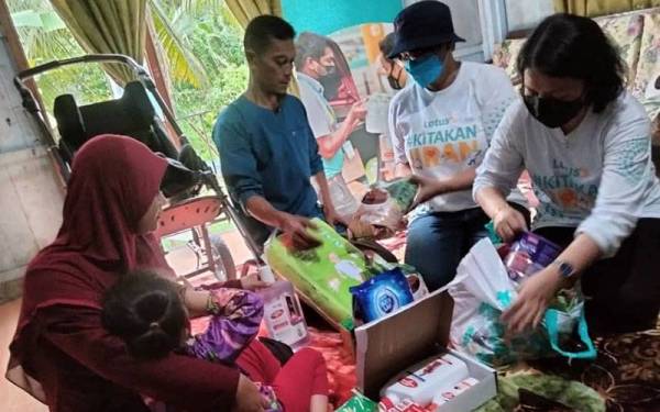 Siuew Luan (kanan) dan Zakiah Hanim menyampaikan sumbangan kerusi roda dan barangan keperluan harian kepada Nurul Aisyah.