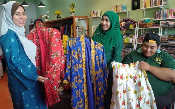 Anas (kanan) melihat kebaya Mami Jarum yang diwakafkan Kartina (dua kanan) kepada Butik Qasehku.com di Taman Ria Jaya Sungai Petani Kedah.