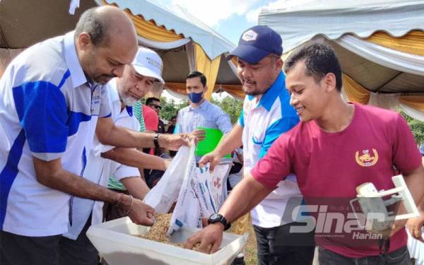 Nagulendran (kiri) dan Abdul Rahim (dua dari kiri) membuat persediaan memasukkan benih padi untuk ditaburkan menggunakan dron selepas Majlis Simbolik Penyerahan Benih Padi IS21 Kepada Pesawah Pertubuhan Peladang Kawasan Machang di Kampung Bukit Tiu pada Ahad.