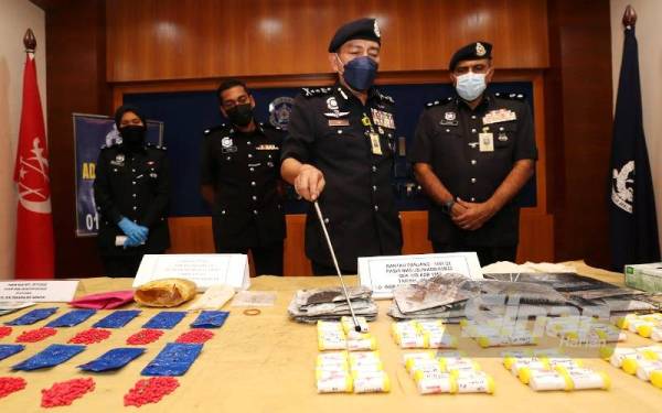 Muhamad Zaki (dua dari kanan) menunjukkan botol-botol berisi serbuk putih dipercayai dadah jenis heroin yang dirampas oleh polis.