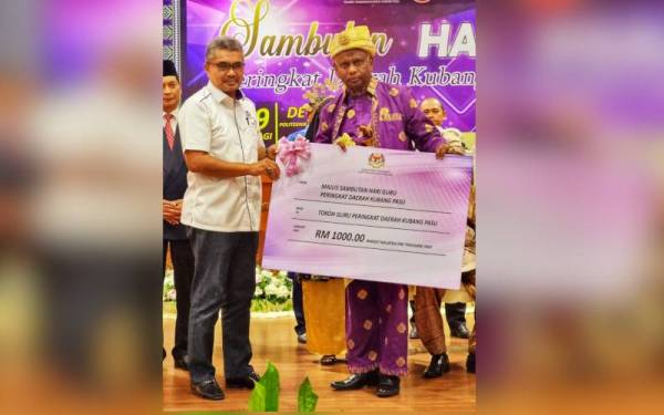 Zainol Abidin (kanan) menerima replika cek daripada Pengerusi Yayasan Pelajaran Mara Datuk Mohd Razman Yaacob ketika Majlis Sambutan Hari Guru Peringkat Daerah Kubang Pasu yang diadakan pada Rabu.