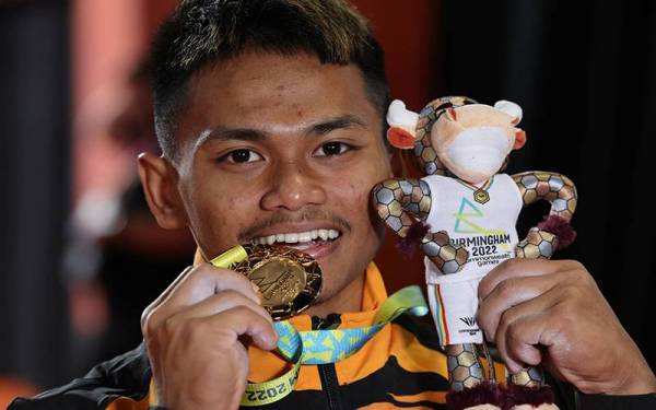 Atlet angkat berat negara Mohamad Aniq Kasdan menunjukan pingat emas pertama negara dalam kategori 55kg pada Sukan Komanwel Birmingham 2022 di Dewan NEC 1 pada Sabtu. - Foto Bernama 