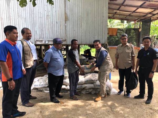 Khairul Shahril (dua dari kanan) dan Yusri (kanan) melihat penduduk menyusun guni berisi pasir yang dibina bagi menghalang arus banjir menghempas rumah mereka.