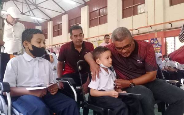 Mohd Razman berbual dengan Muhammad Kamil dan Muhammad Aiman (kiri) semasa menyampaikan sumbangan Yayasan Pelajaran Mara di Sekolah Kebangsaan Kuala Kupang, di Baling pada Isnin.