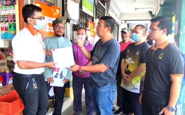 Awalludin (tiga dari kanan) menyerahkan memorandun bantahan kepada penolong pengurus sebuah kedai serbaneka di Nilai Perdana, Nilai.