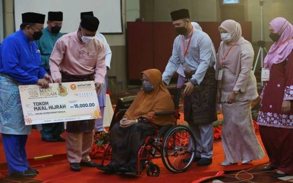 Balu Allahyarham Ismail, Yah Othman, 77 (berkerusi roda) menerima anugerah Maal Hijrah Peringkat Kedah 2022 bagi pihak suaminya daripada Wan Salim di sebuah hotel pada Selasa.