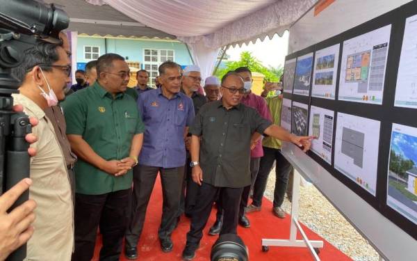 Muhammad Sanusi (tiga kanan) mendengar taklimat ketika Majlis Pecah Tanah Projek Rumah Mangsa Banjir Tragedi Kepala Air Lata Celak Kampung Iboi di Desa Keda Kampung Sadek pada Rabu.