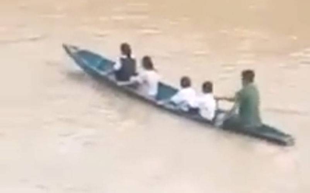 Maratin membawa murid menyeberang Sungai Bengkoka, Pitas, dengan menaiki sampan untuk mereka ke sekolah.