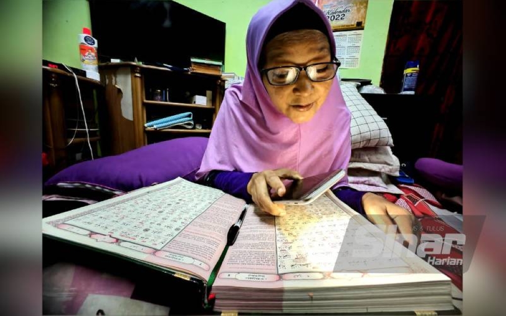 Padilah yang menghadapi masalah penglihatan menggunakan lampu daripada telefon bimbit ketika membaca al-Quran.