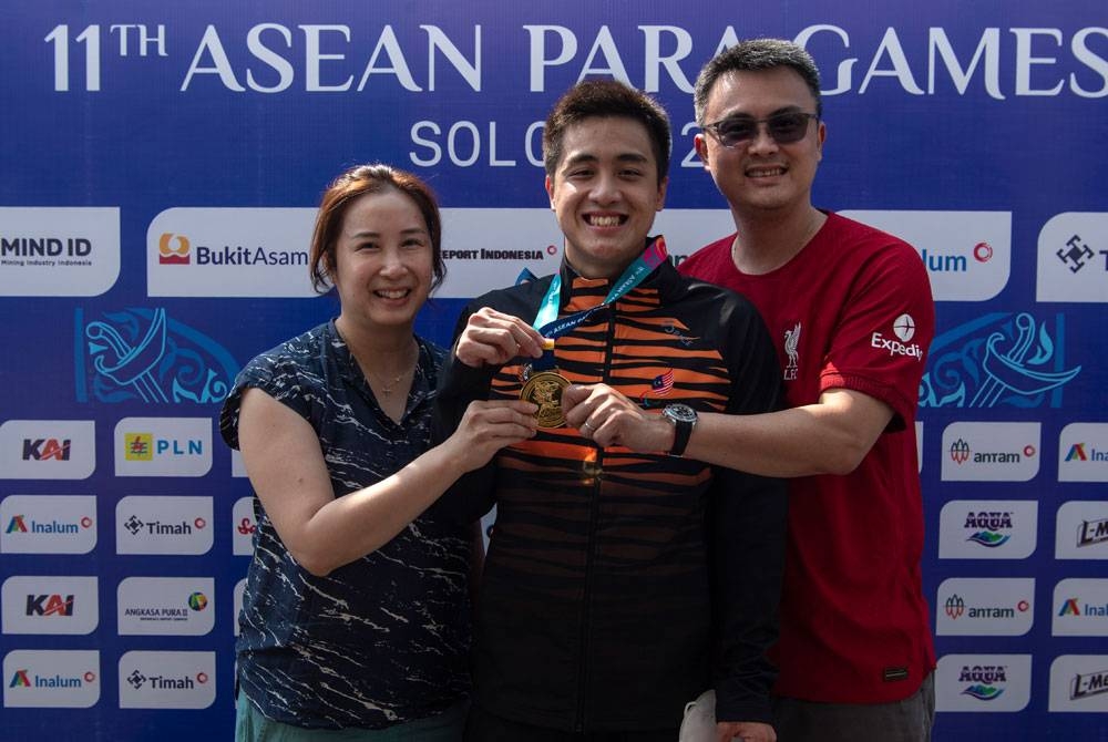 Ethan, Thau Yong (kanan) dan Christina (kiri) bersama pingat emas dimenanginya dalam acara renang 200m gaya bebas lelaki (S14) pada temasya APG 2022 di Pusat Renang Jatidiri pada Khamis. - Foto Bernama