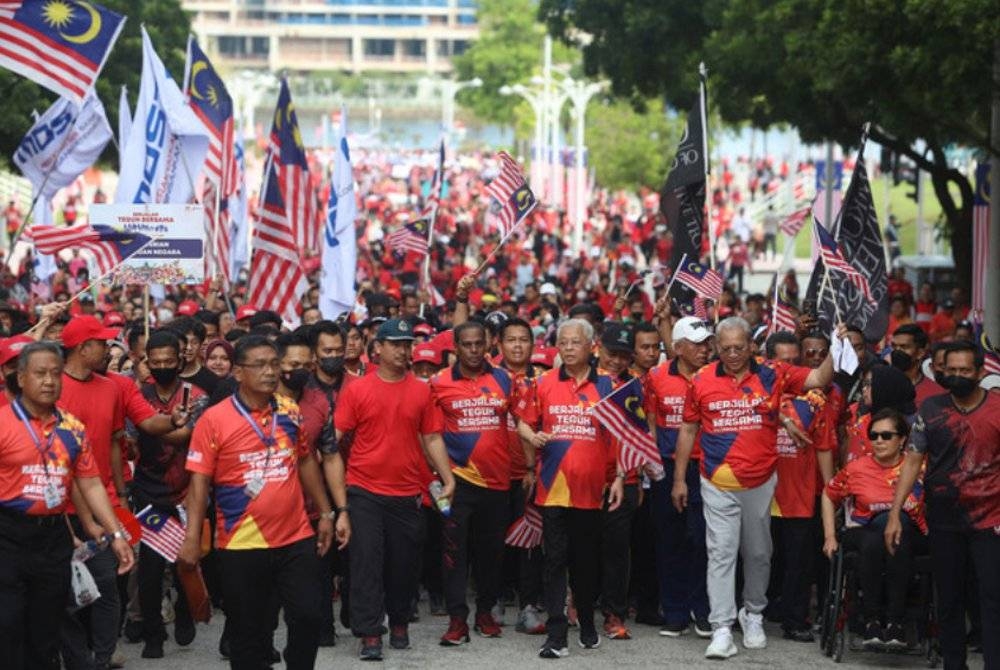 Perdana Menteri, Datuk Seri Ismail Sabri Yaakob (tengah) berjalan sambil mengibarkan Jalur Gemilang pada Program&amp;#039;Berjalan Teguh Bersama&amp;#039; sempena majlis pelancaran Bulan Kebangsaan dan Kibar Jalur Gemilang 2022 di Dataran Putra pada 30 Julai lalu. - Foto Bernama