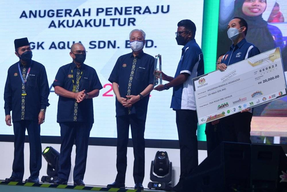 Ismail Sabri (tengah) menyampaikan Anugerah Peneraju Agrikultur kepada wakil GK Aqua Sdn Bhd pada Majlis Perasmian Pameran Pertanian, Hortikultur dan Agro-Pelancongan Malaysia (MAHA) 2022 di Maeps pada Sabtu. Hadir sama, Ronald Kiandee (dua dari kiri). - Foto Bernama 