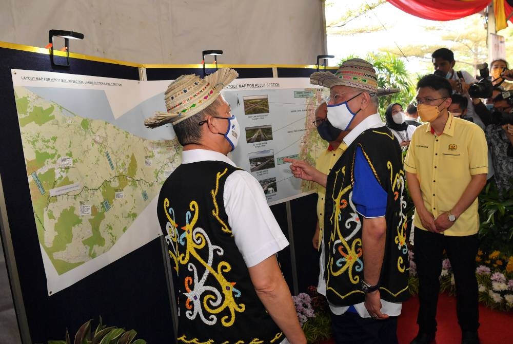  Perdana Menteri Datuk Seri Ismail Sabri Yaakob mendengar penerangan dari Menteri Kanan Kerja Raya Datuk Seri Fadillah Yusof mengenai Lebuhraya Pan Borneo Sarawak Seksyen Pujut (WPC11) pada majlis perasmian pembukaannya, pada Ahad. - Foto Bernama 