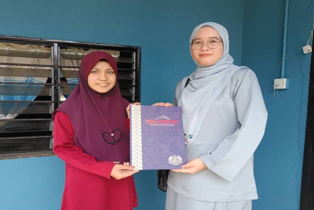 Syazwani (kanan) menyerahkan surat tawaran PTSS Perlis kepada Umi Aqilah di rumahnya dekat Kampung Chenerai Baling pada Jumaat. - Foto PTSS