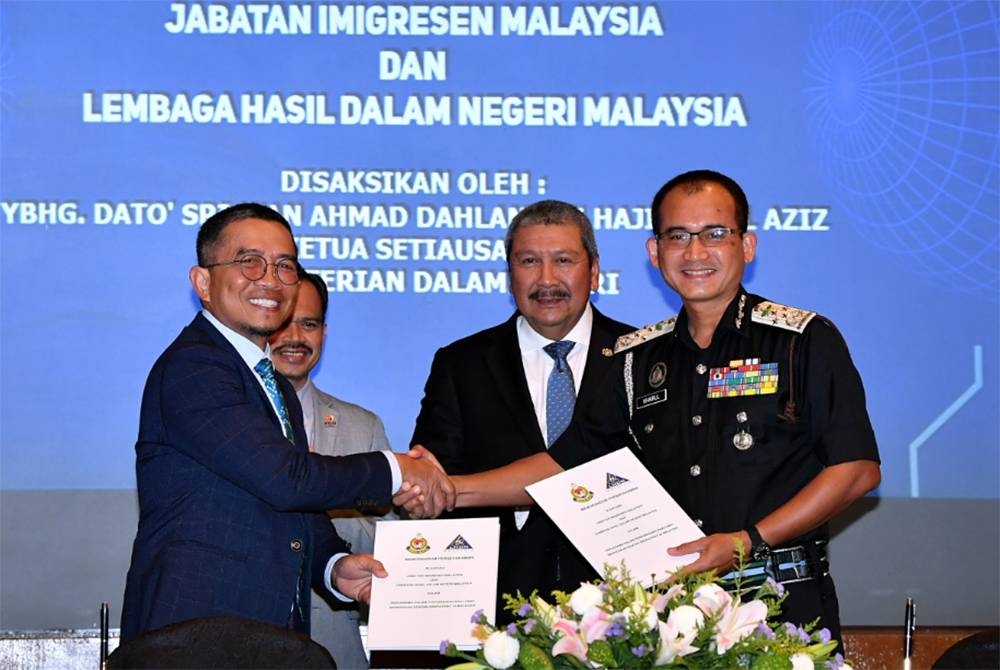 Wan Ahmad Dahlan menyaksikan Majlis Menandatangani Memorandum Persefahaman antara Jabatan Imigresen Malaysia yang diwakili Khairul Dzaimee (kanan) dan Lembaga Hasil Dalam Negeri yang diwakili Mohd Nizom (kiri) di Cyberjaya, pada Selasa. - Foto Bernama