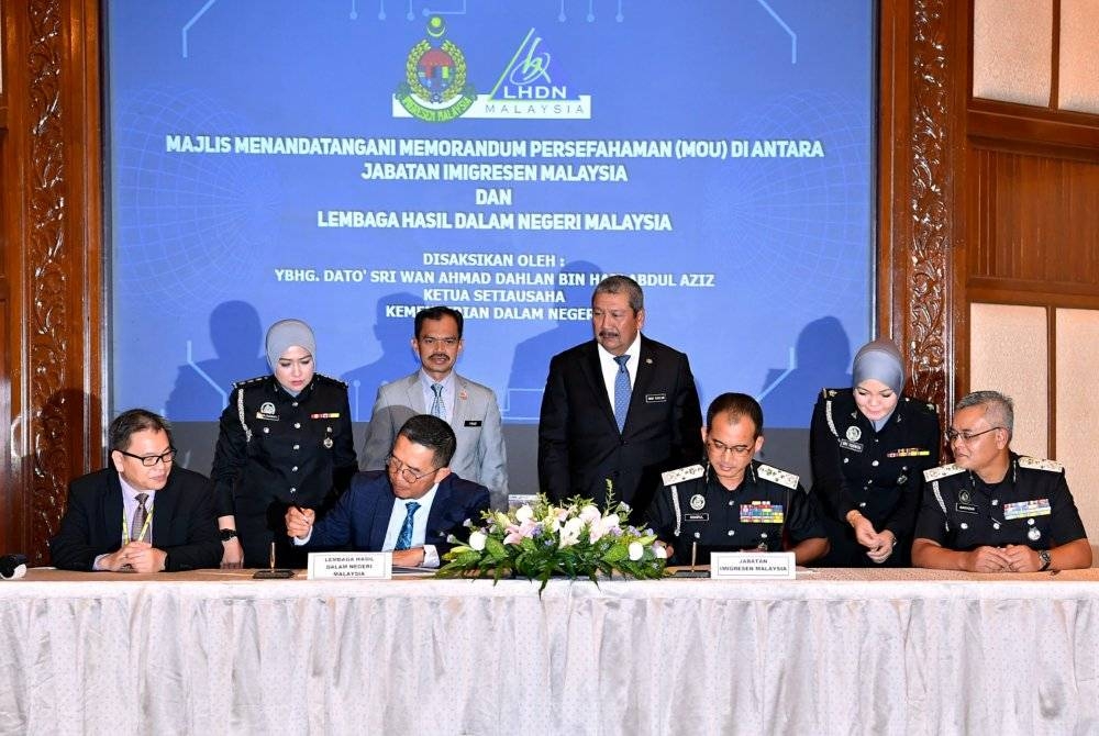 Wan Ahmad Dahlan menyaksikan pertukaran MoU antara Jabatan Imigresen Malaysia yang diwakili Khairul Dzaimee (duduk, dua kanan) dan LHDN yang diwakili Mohd Nizom (duduk, dua kiri) di Cyberjaya pada Selasa. - Foto Bernama 