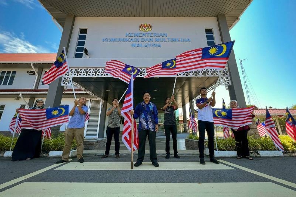  Ab Rasil (empat dari kiri) bersama petugas-petugas bergambar sambil mengibarkan Jalur Gemilang di hadapan bangunan Kompleks Kementerian Komunikasi dan Multimedia Malaysia Labuan pada Khamis. -Foto Bernama
