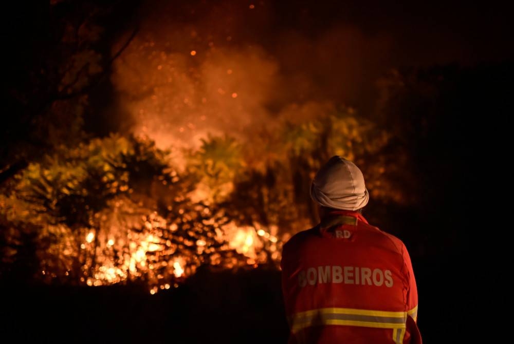 Seorang anggota bomba memadamkan kebakaran hutan di Folgosinho, Gouveia, Portugal pada Jumaat. - Foto EPA