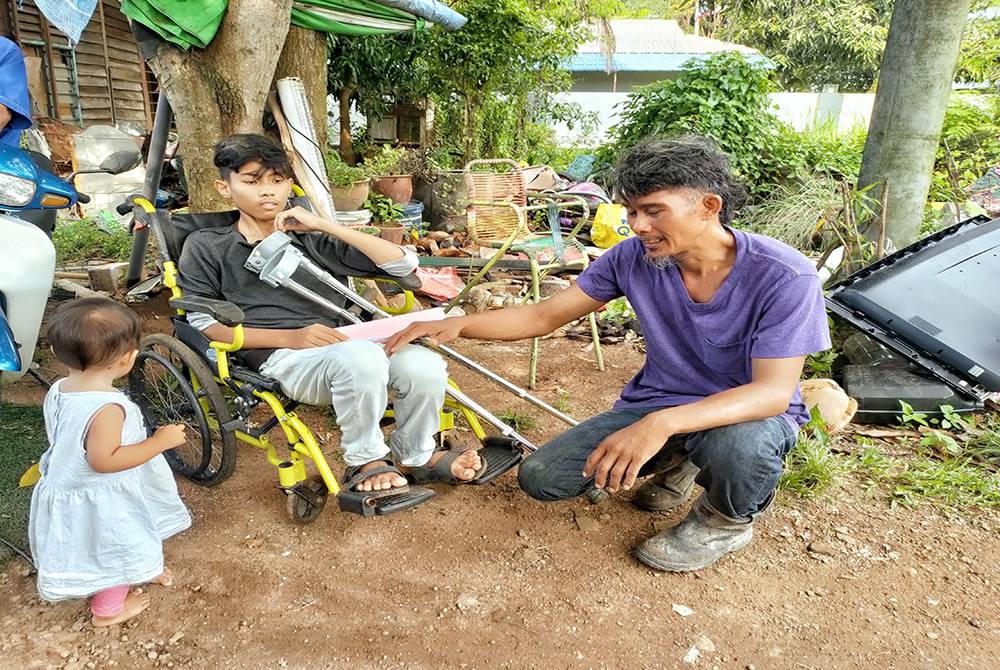 Mohd Amirul menggunakan kerusi roda bersama bapa tirinya, Mohd Afrizal.