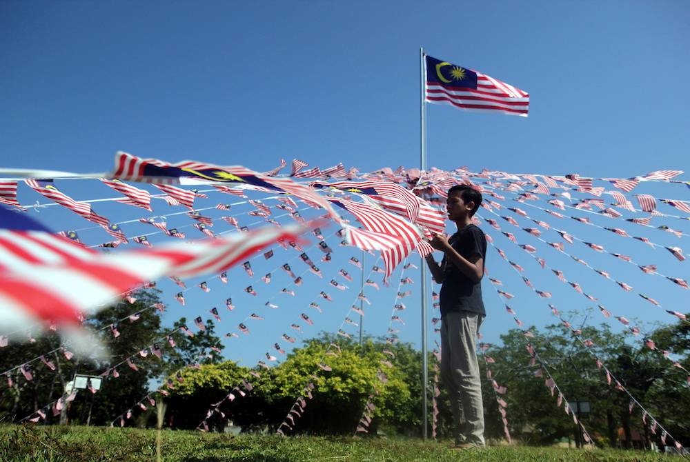 Noah Muhammad Ar Rayyan Mohd Norul Nubhan, 14, tertarik dengan hiasan Jalur Gemilang yang dipasang di bulatan Taman Perumahan Bandar Putra, Kuantan pada Ahad. - Foto Bernama