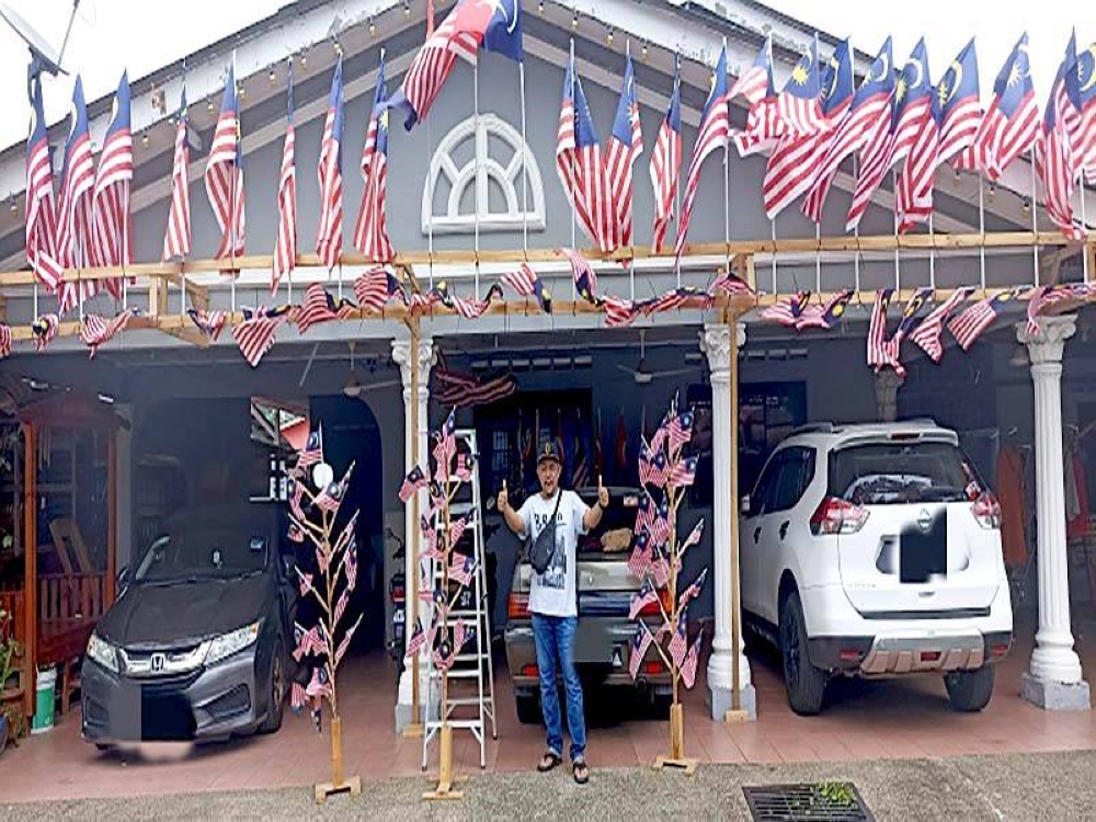 Hassri dihadapan rumahnya di Kampung Bendahara Johor Bahru yang dipenuhi Jalur Gemilang.