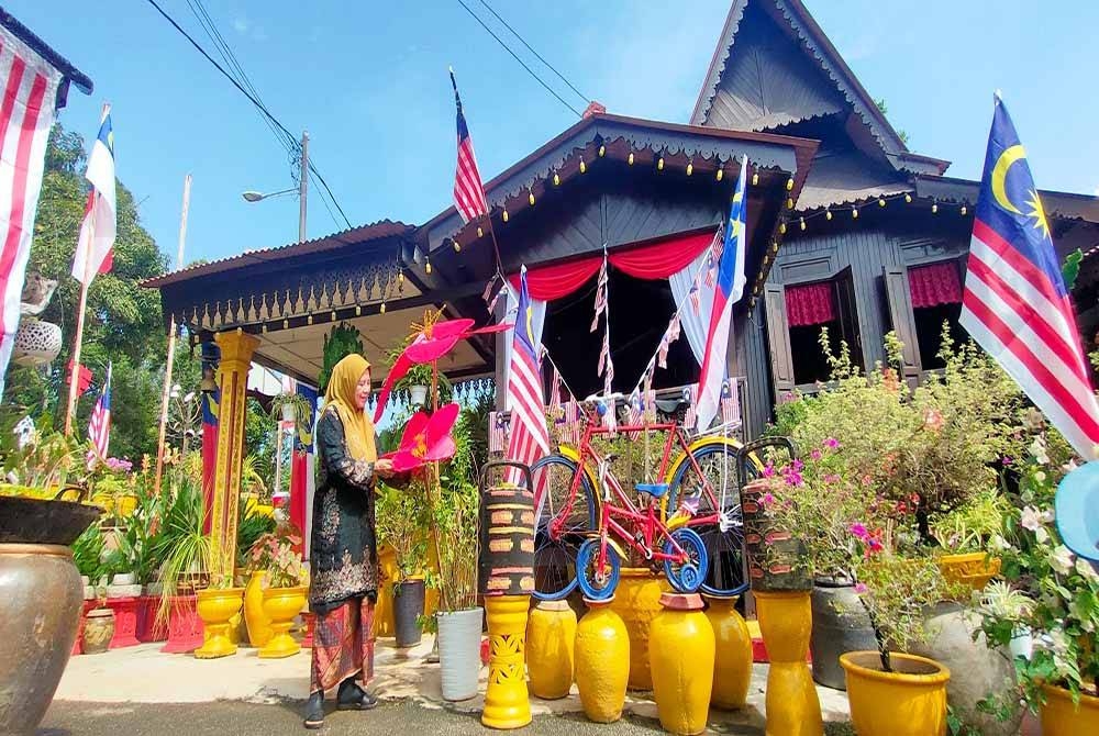 Rahimah menunjukkan replika Bunga Raya yang dibentuk menggunakan kain turut menghiasi halaman rumahnya.