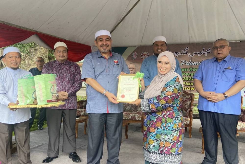 Dr Izani (tiga dari kiri) menyampaikan hadiah dan sijil Johan Kempen Premis Makanan Terbersih 2022 kepada pemilik kedai makan, Noriza Yusof (dua dari kanan).