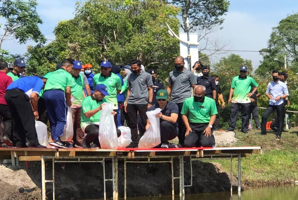 Zainal Abidin (depan, kanan) mengiringi Tengku Hassanal Ibrahim Alam Shah ( depan, tengah) melepaskan benih ikan ke dalam tasik di Taman Tasik Sultan Abu Bakar sempena Pelancaran Kempen Penanaman 100 Juta Pokok Peringkat Daerah Pekan di sini pada Selasa.