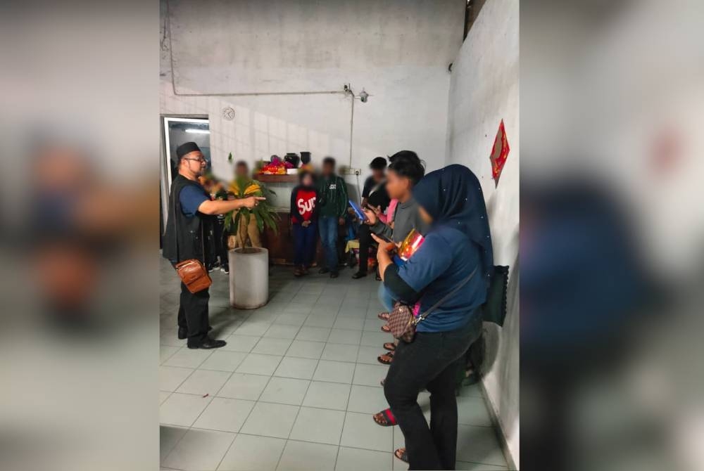 Zaiferi (kiri) memeriksa identiti 10 individu yang ditahan dalam serbuan awal pagi Selasa.