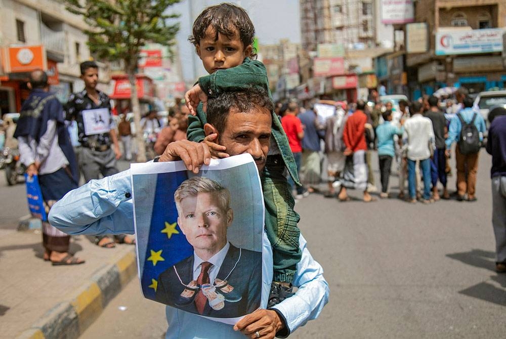 Penunjuk perasaan memegang gambar wakil khas PBB, Hans Grundberg serta menuntut badan dunia menamatkan sekatan di kawasan yang dikawal pemberontak Houthi. - AFP