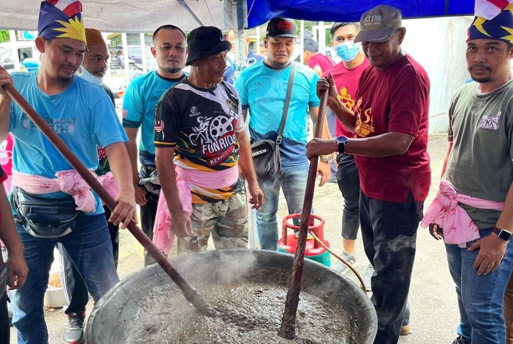 Hanyan (dua dari kanan) mengacau bubur asyura sempena program memasak bubur asyura peringkat IPD Kemaman bersama komuniti Balai Polis Chukai 2022 pada Sabtu.