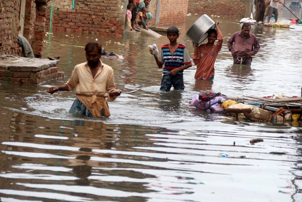 Orang ramai melalui kawasan banjir selepas hujan lebat melanda di Hyderabad, Pakistan pada Jumaat. - Foto EPA