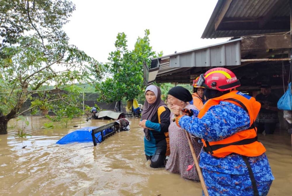 Anggota APM membantu penduduk yang dilanda banjir kilat di Kampung Laut Batu 10, Skudai, Johor Bahru, termasuk memindahkan mereka ke PPS di Dewan Kampung Melayu Batu 10.