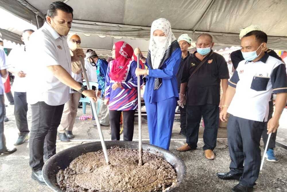 Mohd Shahar (kiri) mengacau bubur asyura ketika merasmikan Program Merdeka @Komuniti di Sekolah Kebangsaan Kadok pada Ahad.