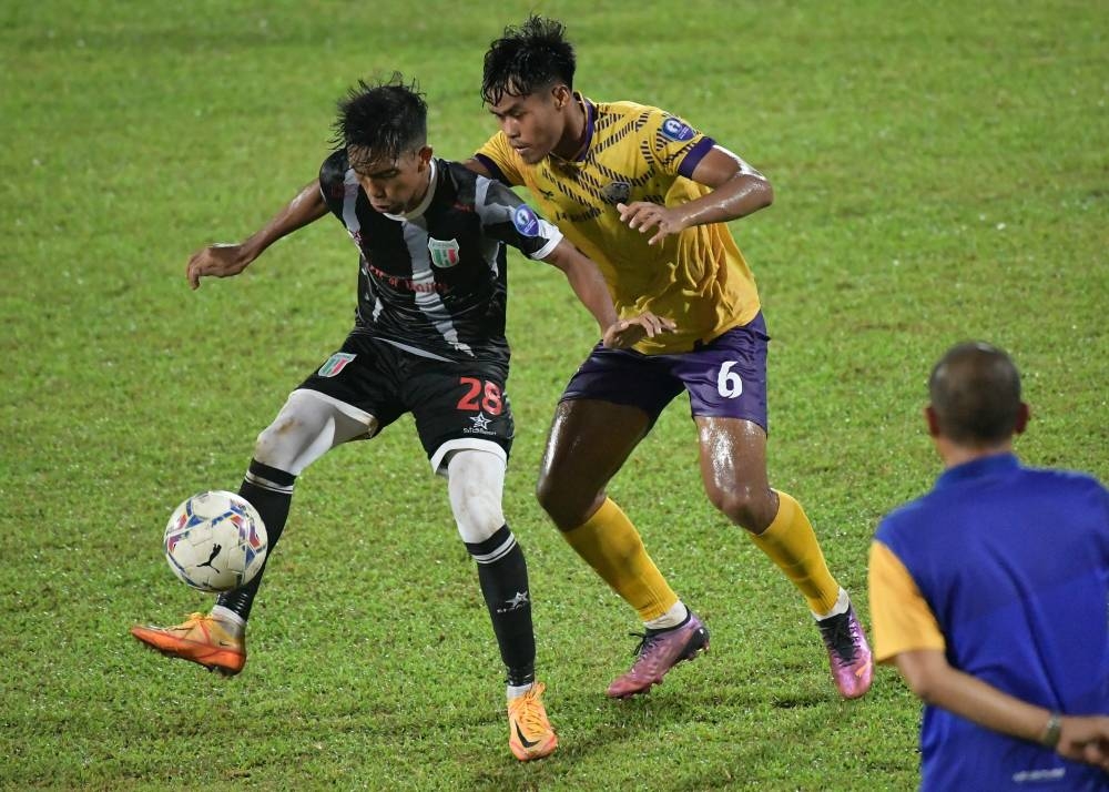 Pemain UiTM FC, Mohammd Hakim Ismail (kanan), cuba mengasak pemain Kuching City FC, Wan Mohammad Faiz Wan Sulaimanpada perlawanan berkenaan. - Foto Bernama
