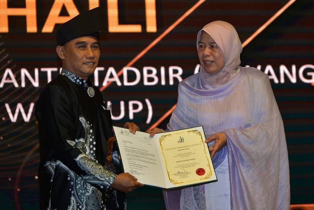 Zuraida (kanan) menyampaikan Anugerah Perkhidmatan Lembaga Lada Malaysia kepada kakitangan Lembaga Lada Malaysia Sarawak, Fauzi Suhaili pada Rabu. - Foto Bernama