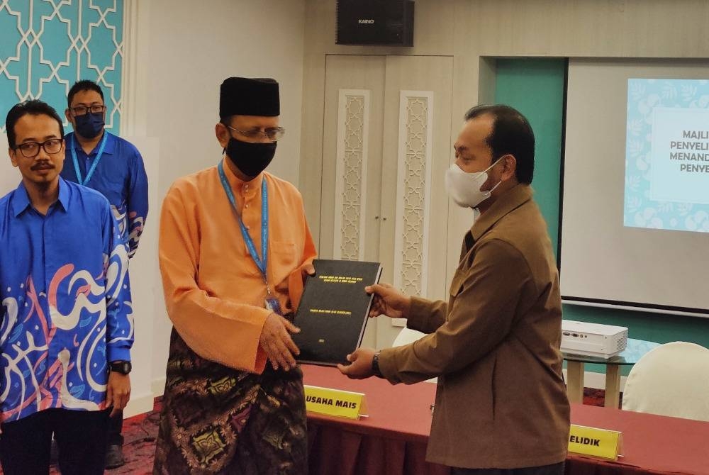 Setiausaha Majlis Agama Islam Selangor (MAIS), Dr Ahmad Shahir Makhtar (dua, kiri) menerima laporan hasil penyelidikan bagi tahun 2021 daripada salah seorang penyelidik (kanan) di Majlis Penyerahan Perjanjian Penyelidikan Tahun 2022 dan Serahan Laporan Hasil Penyelidikan Tahun 2021 di Dewan Anggerik, Hotel De Palma, Seksyen 19, pada Jumaat.