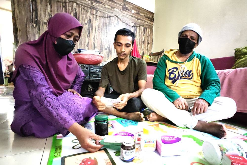 Faris Danial bersama ibu dan bapanya menunjukkan ubat yang diambilnya.