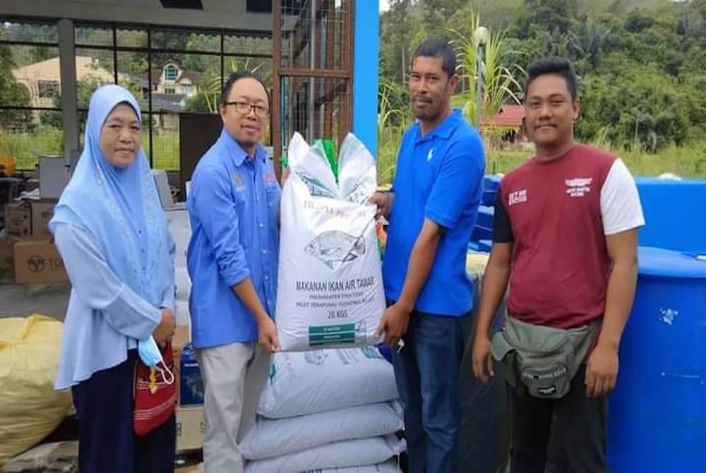 Kasim (dua kiri) menyerahkan bantuan kepada penerima terlibat. -
Foto Pejabat Perikanan Negeri Sembilan.