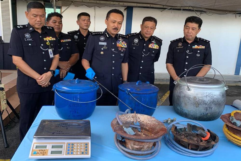 Mohd Yusri (tengah) menunjukkan bahan kimia yang dirampas di sebuah makmal memproses dadah di Tapah pada Jumaat lalu.