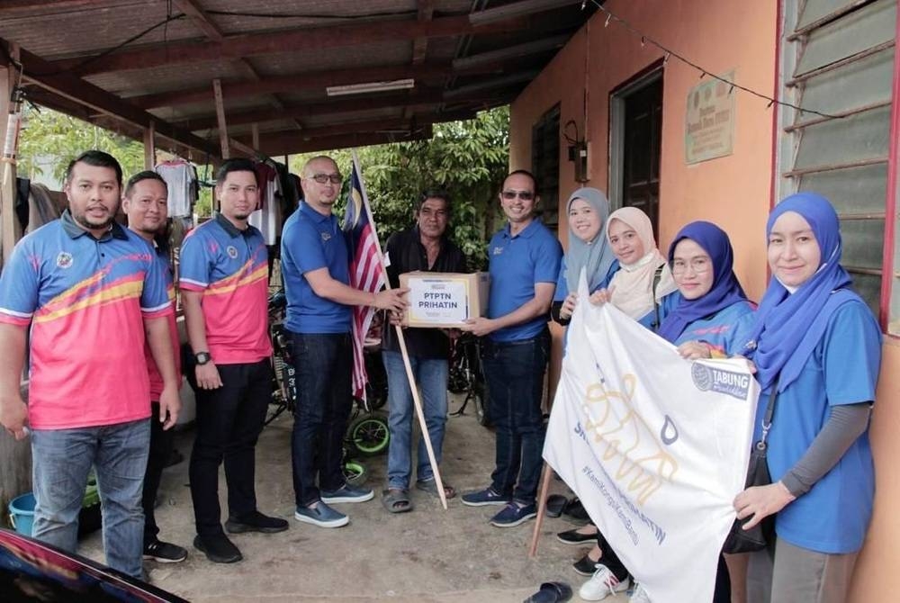 Apli (empat dari kiri) dan Ahmad Dasuki (enam dari kiri) menyampaikan sumbangan kotak makanan kepada salah seorang penduduk kampung sebagai tanda keprihatinan PTPTN.