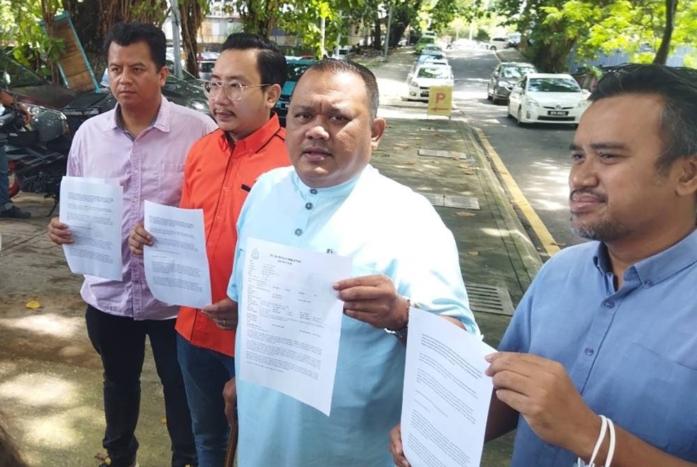 Mohd Sany (dua dari kanan) menunjukkan laporan polis pada sidang akhbar di hadapan IPD Dang Wangi pada Isnin.