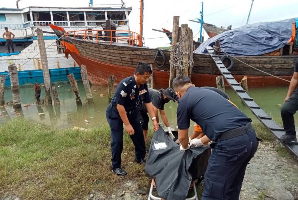 Anggota polis mengangkat mayat seorang pekera bot yang terjatuh dalam laut di Jeti Batu 3, Jalan Minyak Beku di Batu Pahat pada Isnin.