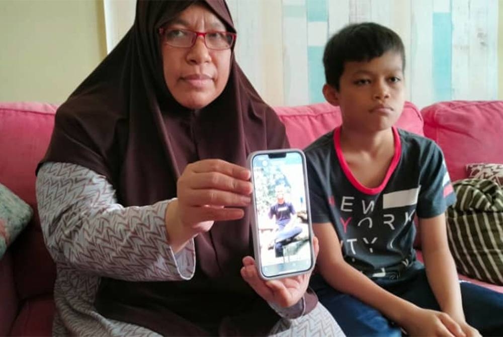 Hizanawati menunjukkan gambar Muhammad Damin selepas Allahyarham ditemui meninggal dunia dalam kebakaran di sebuah tandas awam terbiar di Bandar Puncak Alam Fasa 3 di sini, pada Ahad.