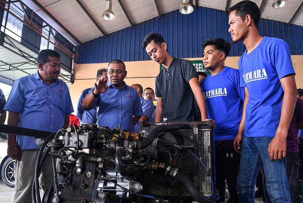 Din (dua dari kiri) bertanya sesuatu kepada pelatih bidang automotif ketika membuat lawatan di Pusat GiatMARA Marang pada Selasa. - Foto Bernama