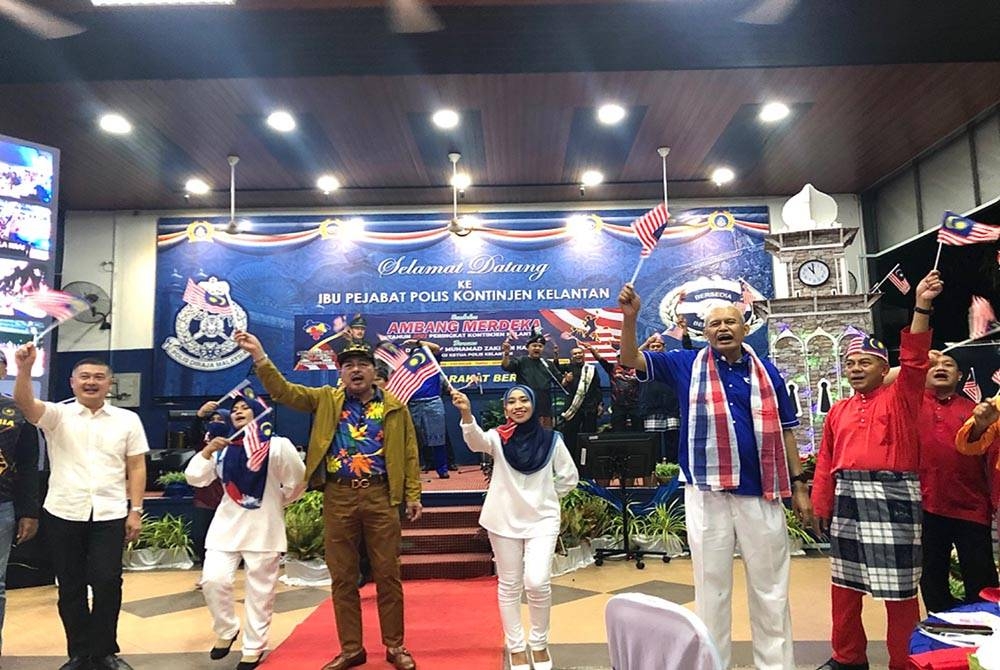 Muhamad Zaki (tiga dari kiri) menyanyikan lagu patriotik semasa Sambutan Ambang Merdeka ke-65 Tahun 2022
di Ibu Pejabat Polis Kontinjen Kelantan, Kota Bharu pada Selasa.