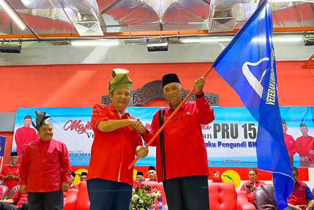 Ahmad Jazlan (kiri) menyerahkan bendera BN semasa merasmikan Majlis Pelancaran Jentera PRU15 Veteran UMNO Negeri Kelantan dan Perasmian Gerak Kerja Keluargaku Pengundi BN di Pasir Mas pada Rabu.