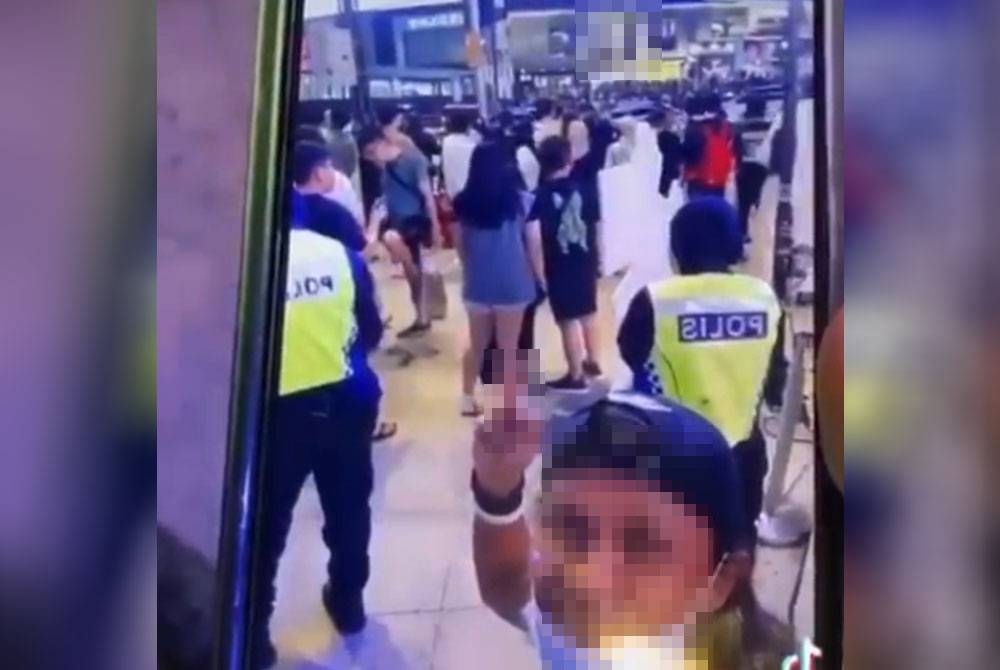 Tangkap layar memaparkan video perbuatan seorang lelaki menunjukkan isyarat lucah kepada anggota polis yang tular di media sosial.