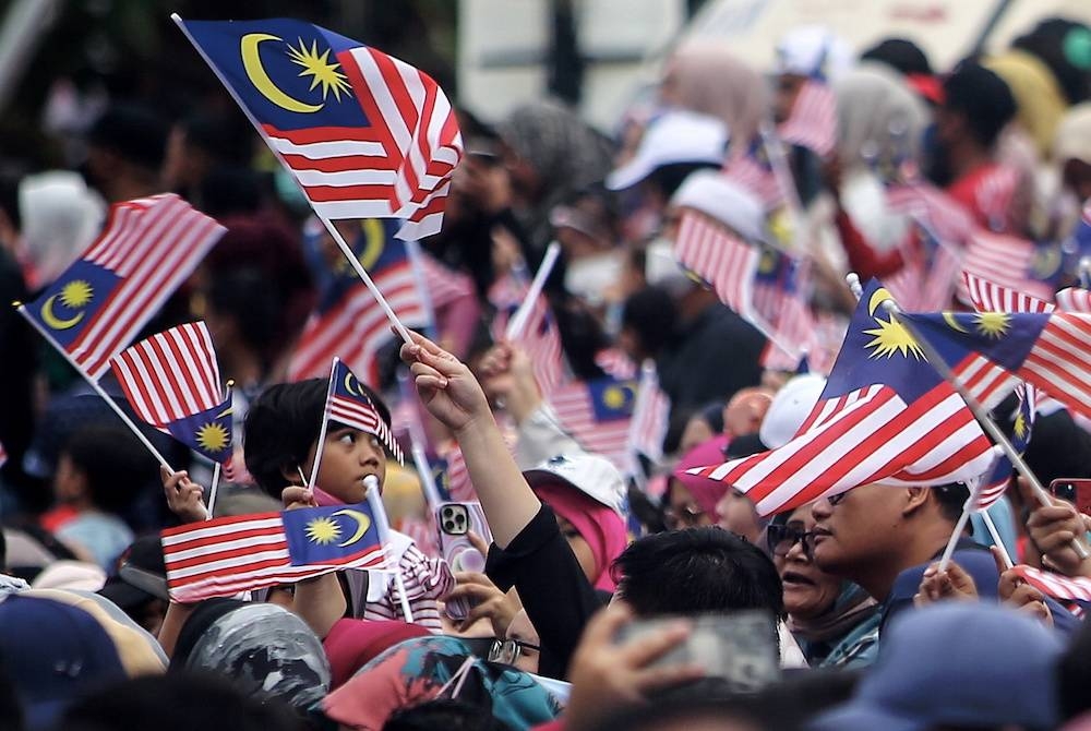 Warga Keluarga Malaysia mengibarkan Jalur Gemilang ketika hadir menyaksikan acara perbarisan dan perarakan Sambutan Hari Kebangsaan 2022 Peringkat Negeri Sembilan pada Rabu. - Foto Bernama